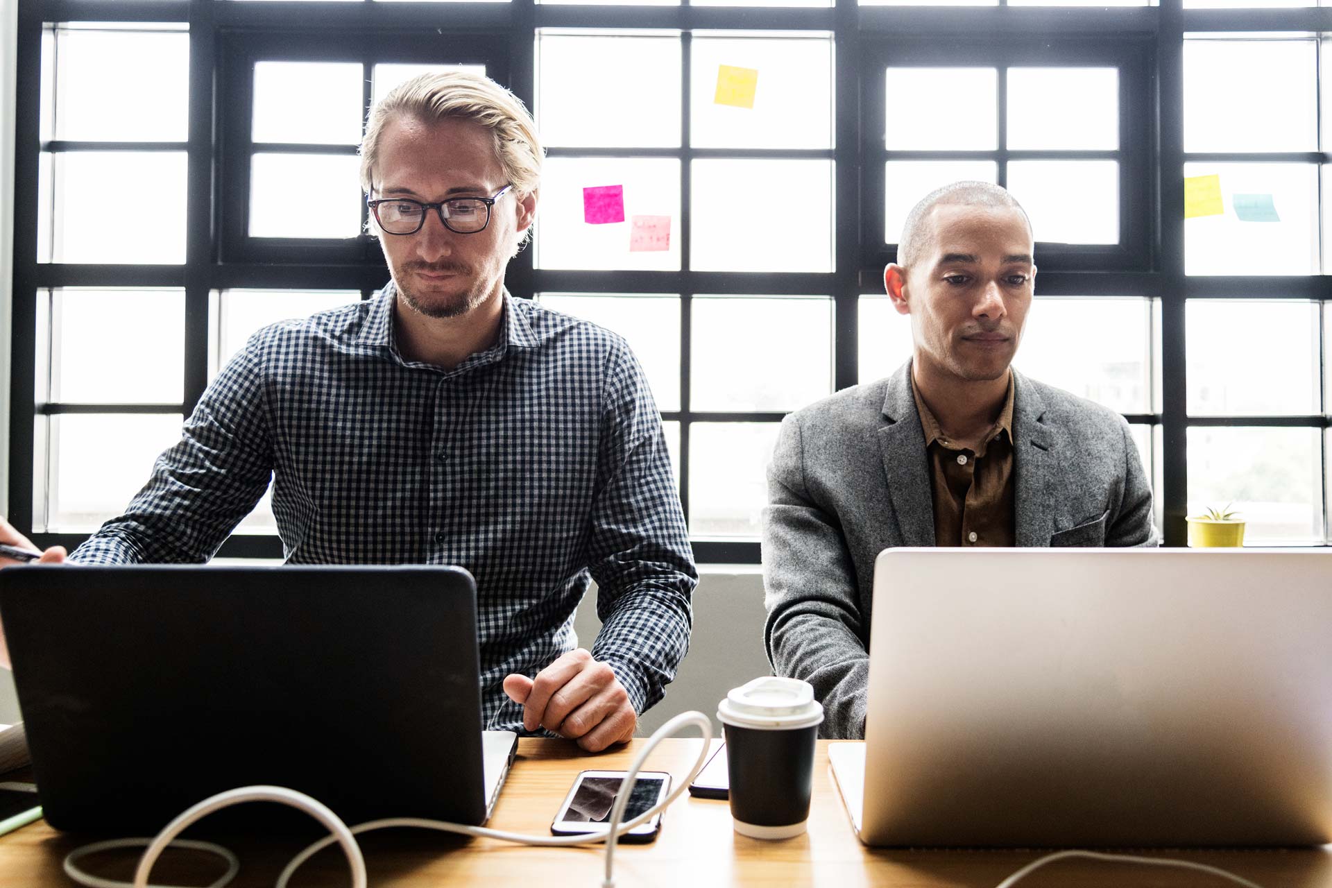 Two colleagues working at their laptops in a bright office